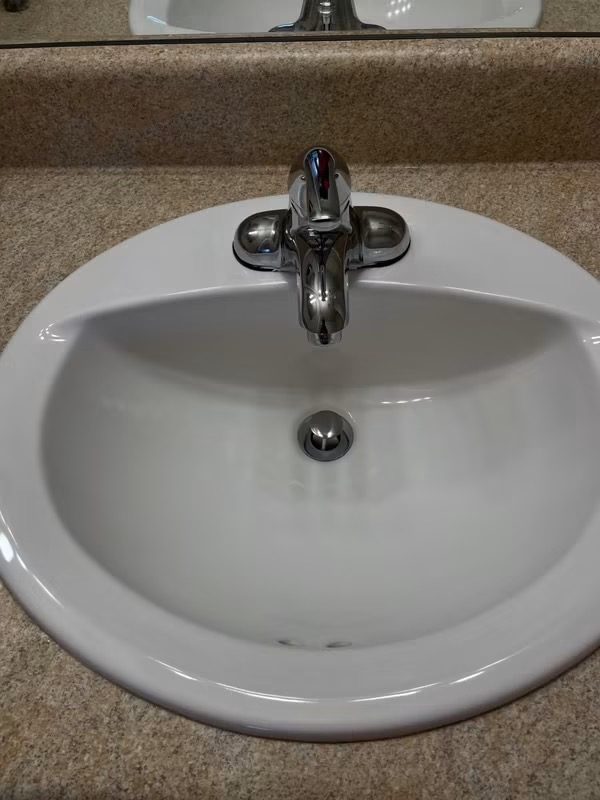 After cleaning: same bathroom sink scrubbed white with a polished, streak-free chrome faucet by Clean & Polished