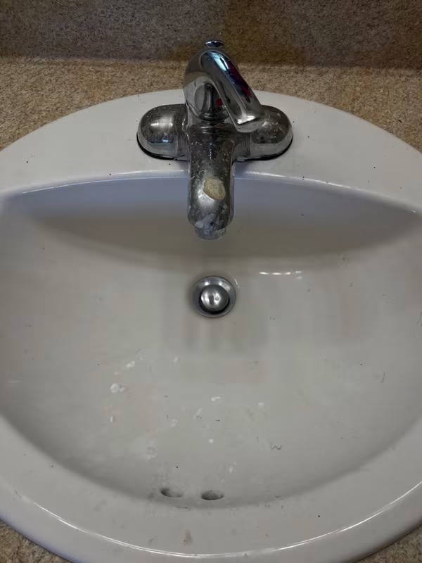Before cleaning: bathroom sink with hard water spots, grime and a dull chrome faucet in a Greater Hartford home